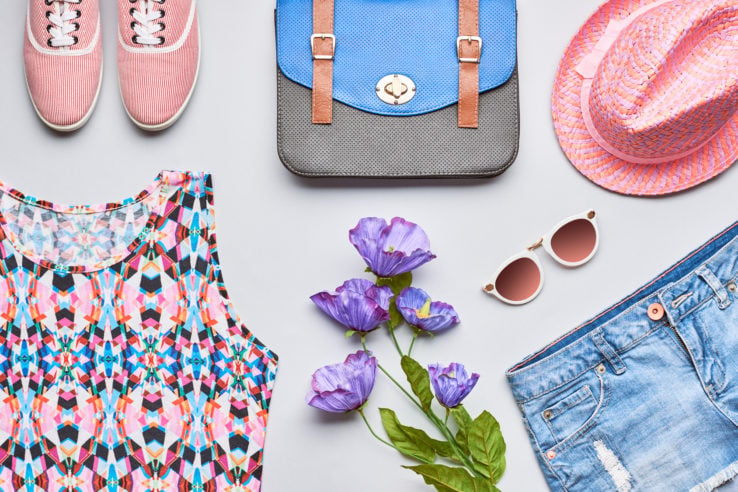Fashion girl clothes accessories set. Stylish hipster, trendy handbag, top, denim, gumshoes, pink hat, sunglasses and flowers. Bright urban summer outfit. Unusual overhead, top view on gray background